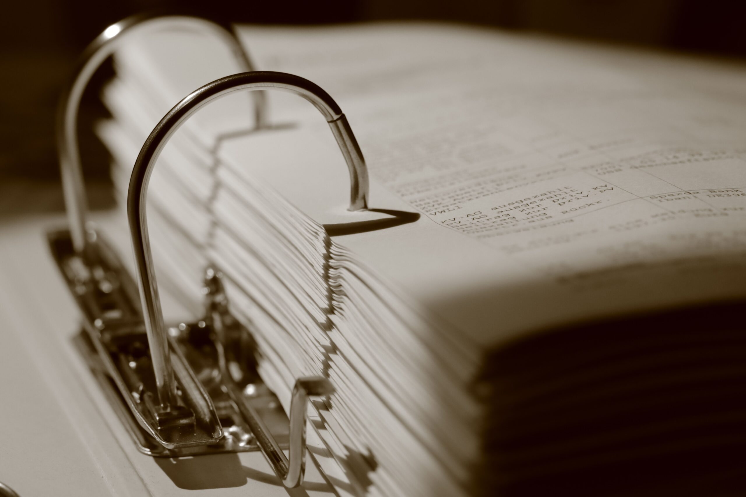 detailed sepia close up of a binder filled with documents, emphasizing texture.